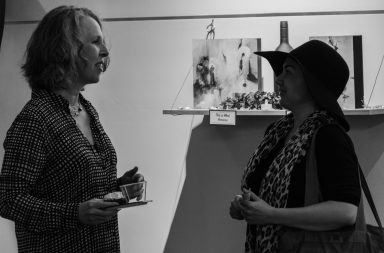 Two people talking face to face in an art gallery.