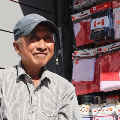 old man wearing hat selling canadian sovenirs