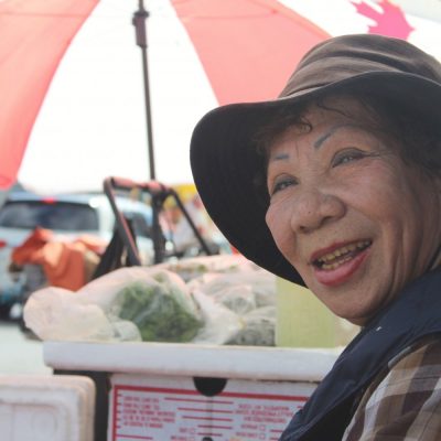 woman wearing hat sells produce on the chinatown street