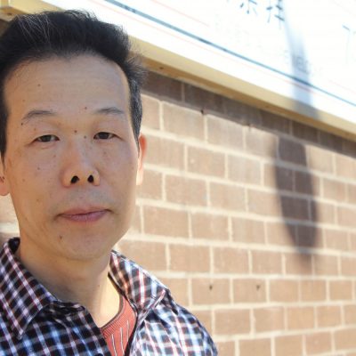 Man standing in front of church sign and brick wall