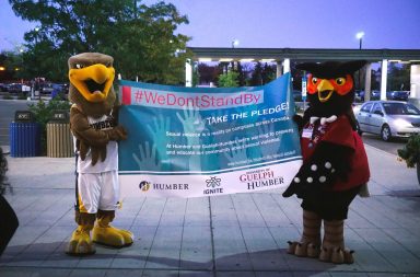 Humber College Mascot Hawk and Univeristy of Guelph-Humber mascot Swoop the owl hold a sign in support of sexual assault survivors