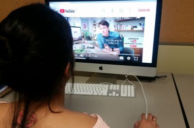 Girl looking at computer with YouTube on it.