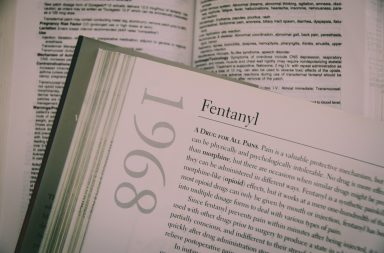 Image of a book open. The page open says 'Fentanyl' as a subheading. The year 1968 is vertical on the margin. The body copy begins by saying "a drug for all pains." There is a book behind the open book and the text is out of focus. The colours are white, grey, black, with a hint of sepia.