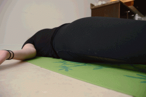Woman lying on back in all black with palms facing up