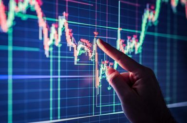 A person touching a computer screen displaying the trend in a stock.