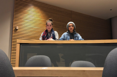 Two students sit at a table in a lecture theatre