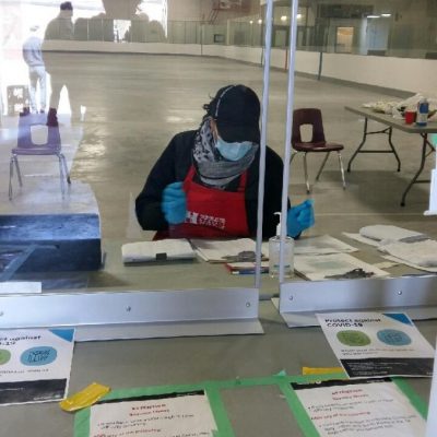 A person at a desk behind a plexiglass screen