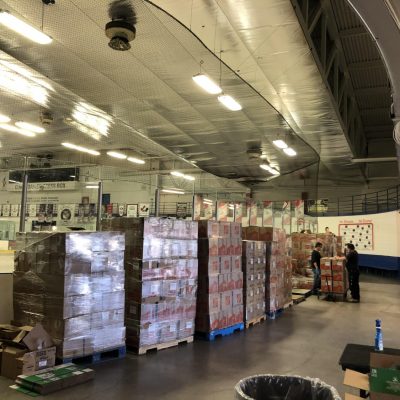 Food bank items await distribution in a hockey arena