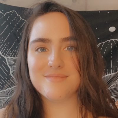 A headshot of a young woman with long brown hair and blue eyes